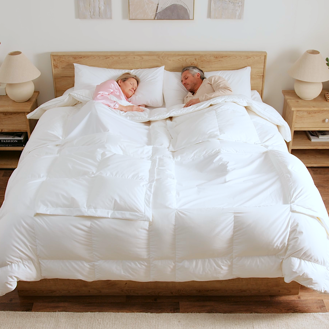Couple sleeping under the Sleeping Dove comforter with different windows open, showing natural cooling for hot and cold sleepers. This is the Sleeping Dove Comforter, the natural cooling comforter.