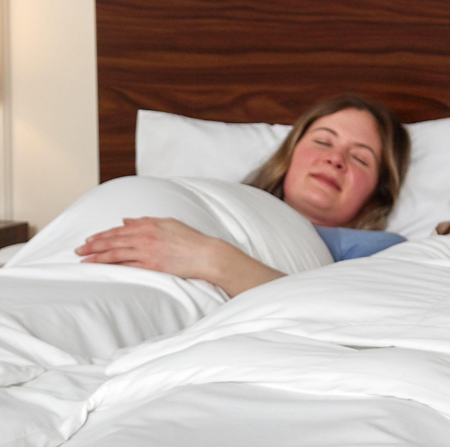 Pregnant woman sleeping comfortably under the Sleeping Dove cooling comforter, ideal for temperature swings during pregnancy