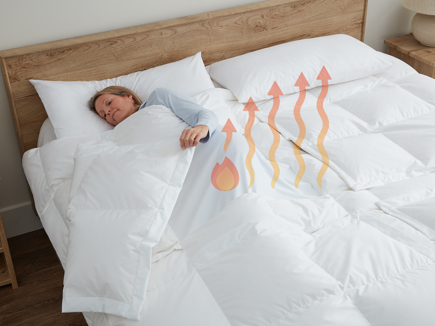 Woman lying in bed under a white Sleeping Dove cooling comforter with heating symbols as one panel is open