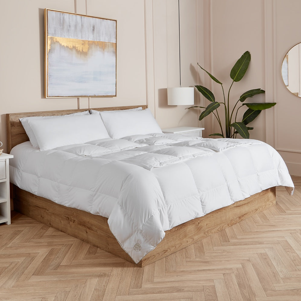 Neatly made bed with white sleeping dove cooling comforter all panels closed in a bedroom setting.