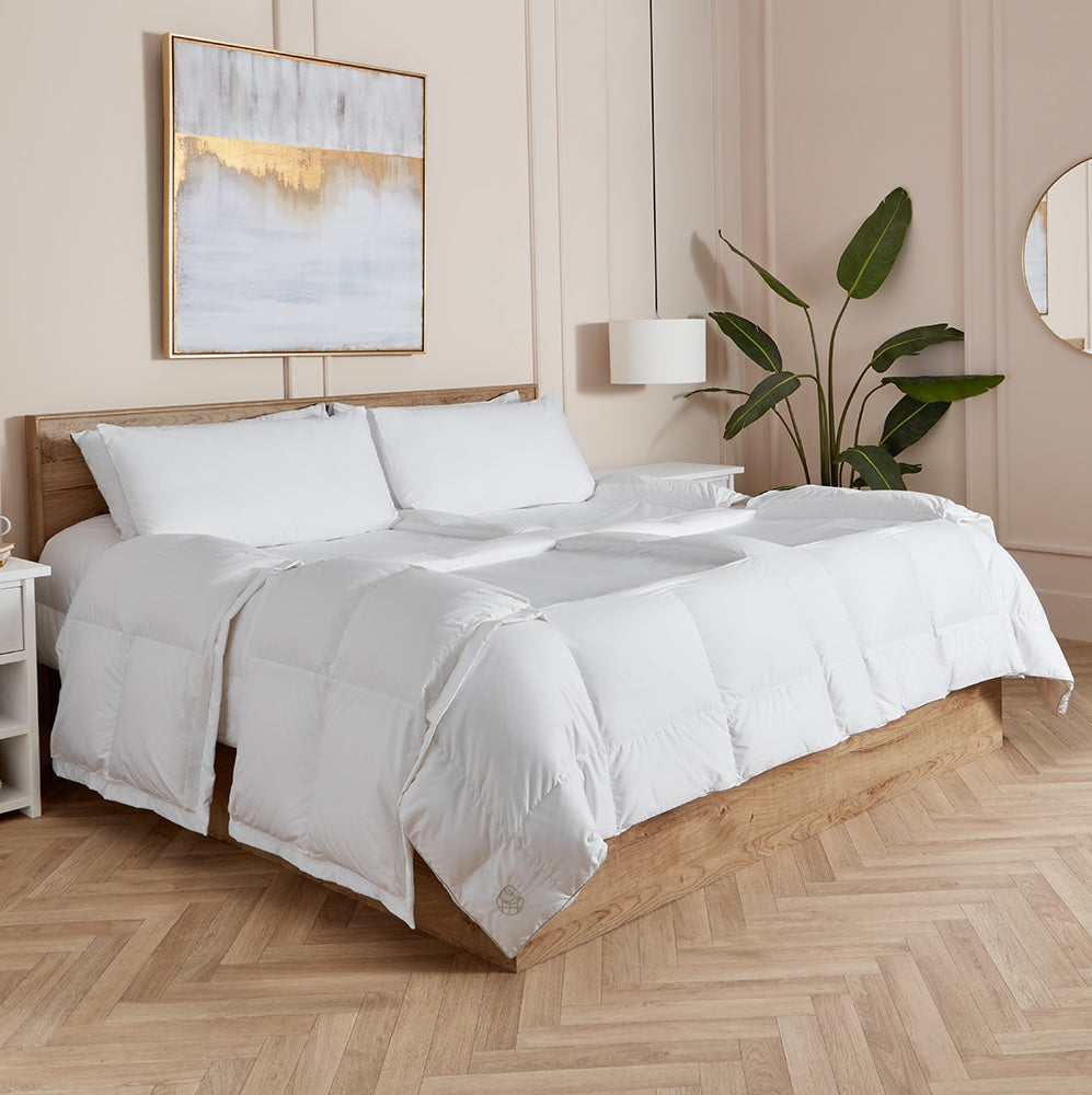 Neatly made bed with white sleeping dove cooling comforter all panels open in a bedroom setting.