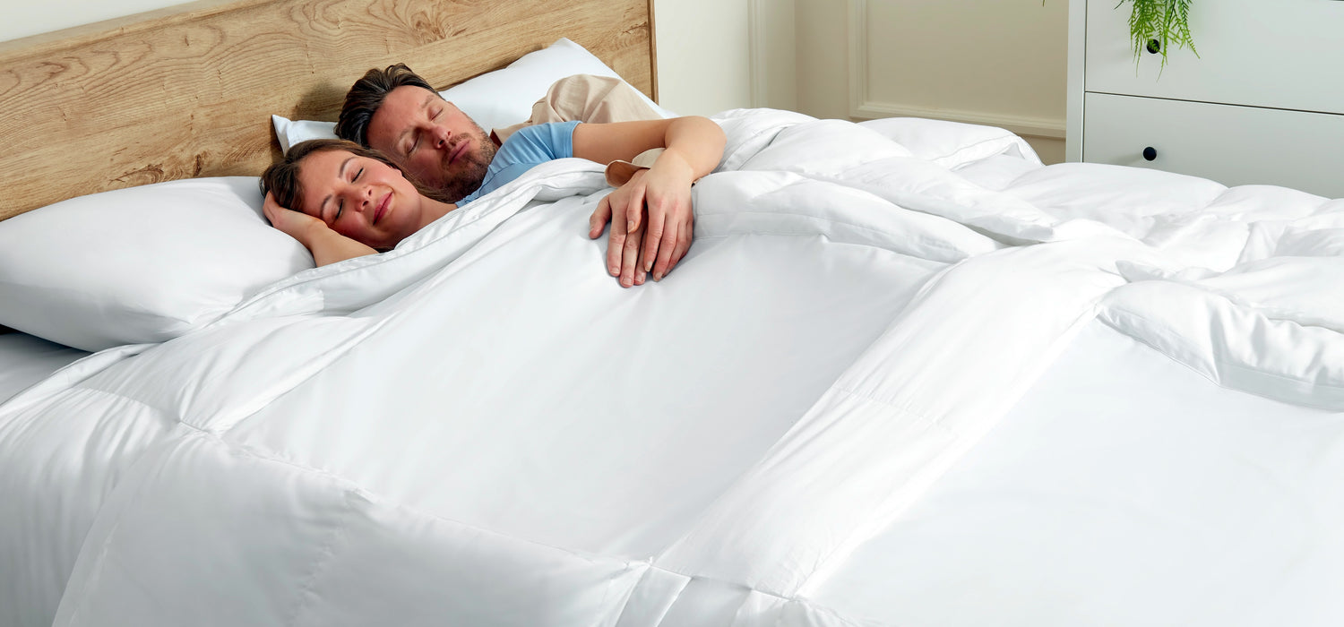 Couple sleeping peacefully under Sleeping Dove,  the cooling comforter  with panels that naturally cools you off