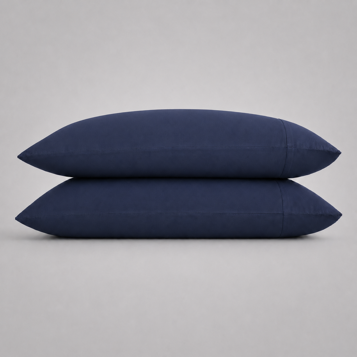 Two navy blue pillowcases stacked on top of each other against a neutral gray background.