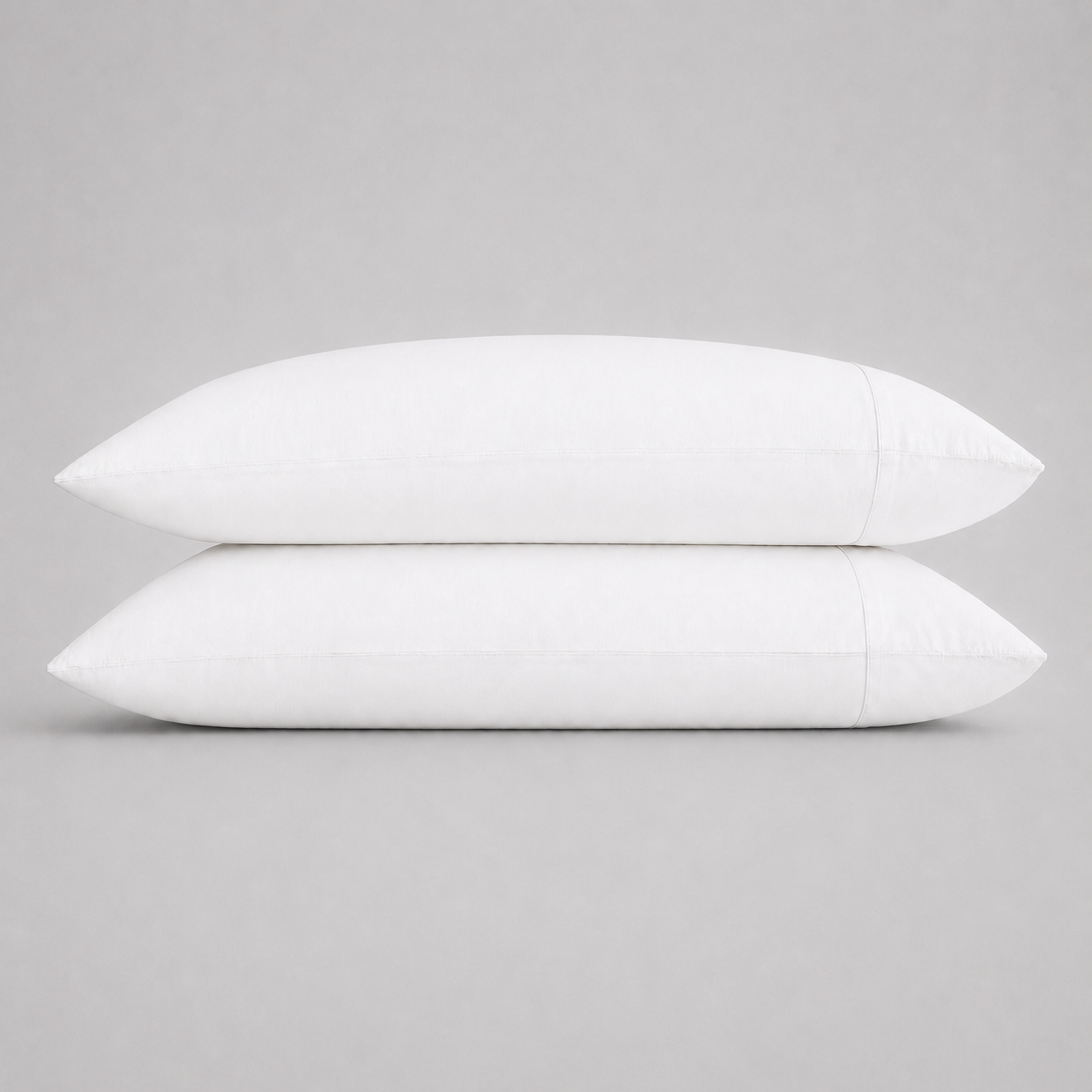 Two plain white rectangular pillows stacked vertically on a neutral light gray background.