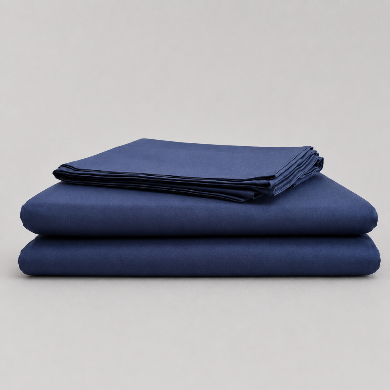 A stack of three folded navy blue sheets or fabric pieces on a light gray studio background.