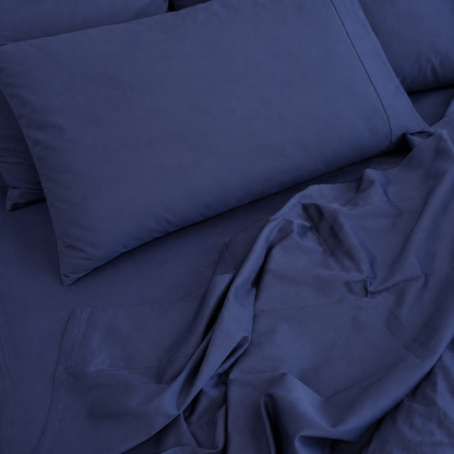 Navy Sleeping Dove bedding set with a pillowcase and rumpled sheets on a bed.