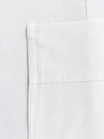 Close-up of a white fabric product showing a folded corner with clean stitching on a matching white background.