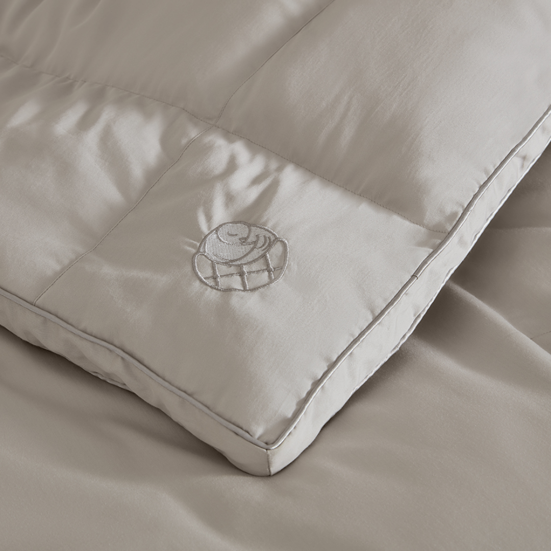 Close-up of Sleeping Dove cooling comforter with embroidered logo, made of breathable cotton for hot sleepers, couples, and pet owners.