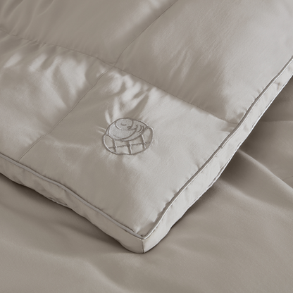 Close-up of Sleeping Dove cooling comforter with embroidered logo, made of breathable cotton for hot sleepers, couples, and pet owners.