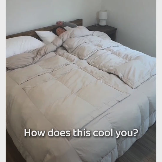A woman lies under a Stone Sleeping Dove comforter with the panel over her chest folded back as animated arrows show heat rising off her; then she spreads the comforter on a bed and opens a panel. On-screen text: How does this cool you? Just open a panel.