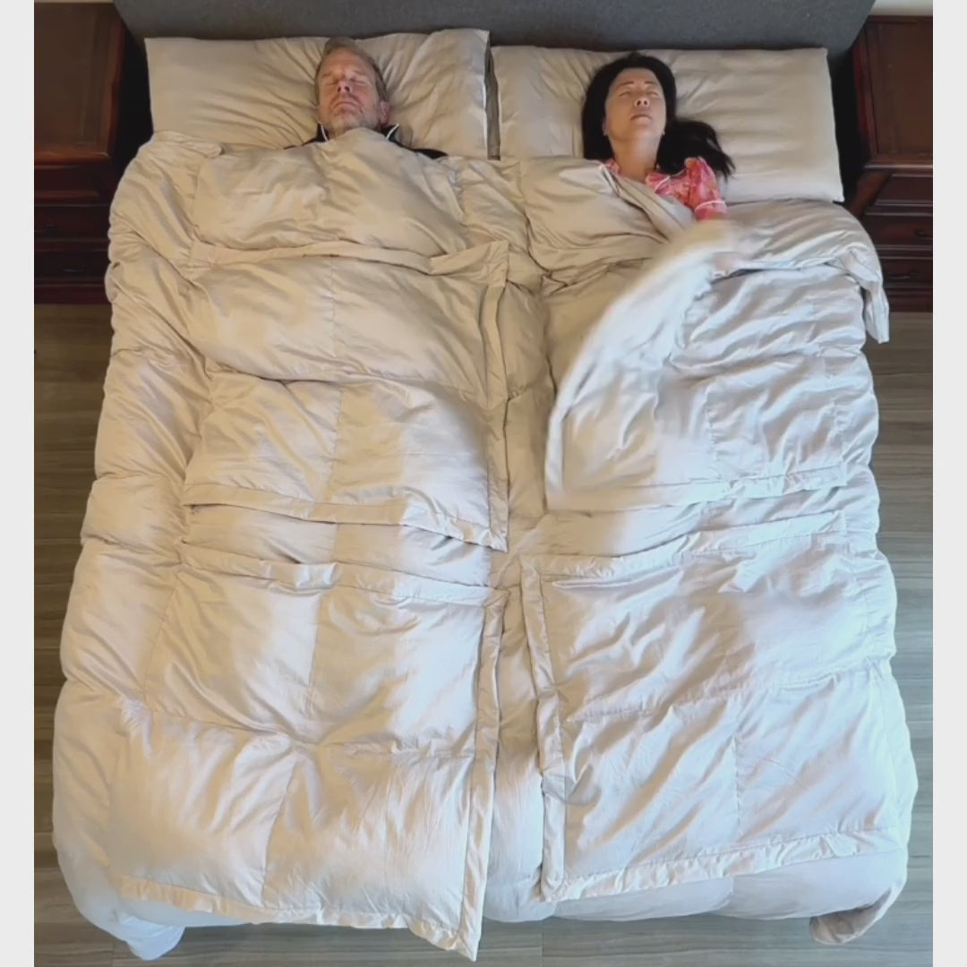Overhead view of a couple under a Stone Sleeping Dove comforter. Each lifts a panel over their own chest or legs, and animated arrows show trapped heat rising away while both stay covered.