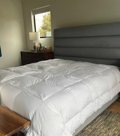 Customer photo of a white Sleeping Dove comforter on a bed with a gray upholstered headboard.